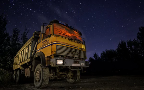 A yellow Iveco truck parked at night under a starry sky, captured in HD for a desktop wallpaper background.