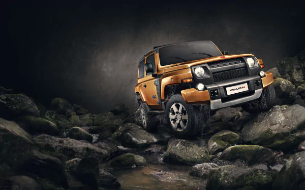 Orange Troller T4 off-road vehicle perched on wet rocks under dramatic lighting — 4K Ultra HD PC desktop wallpaper and background.