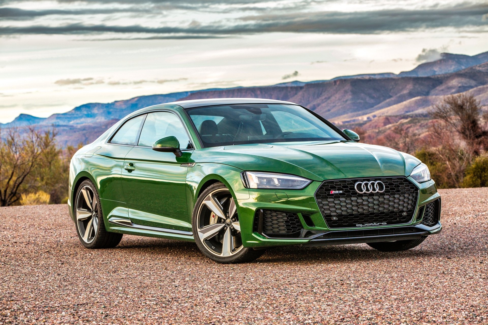 Green Audi RS5 coupe on a gravel turnout with desert mesas and cloudy sky — 4K Ultra HD PC desktop wallpaper background.