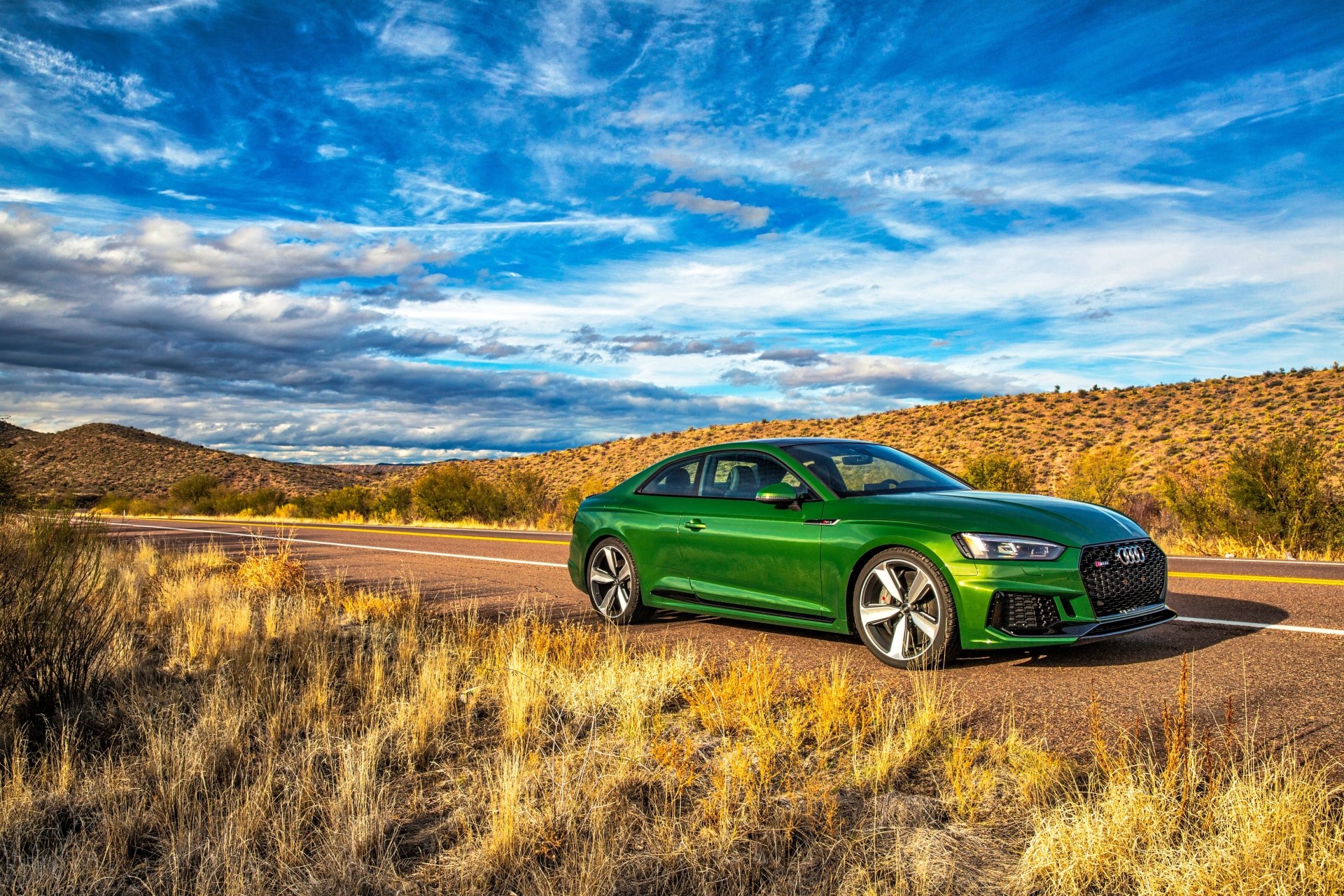A vibrant green Audi RS5 parked on a scenic desert road under a dramatic blue sky, showcased in 4K Ultra HD as a striking desktop wallpaper and background.
