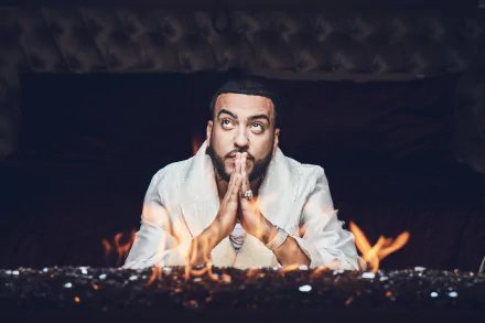 HD wallpaper featuring a person with hands clasped in front of a fire, expressing focus and intensity, suitable as a desktop background.
