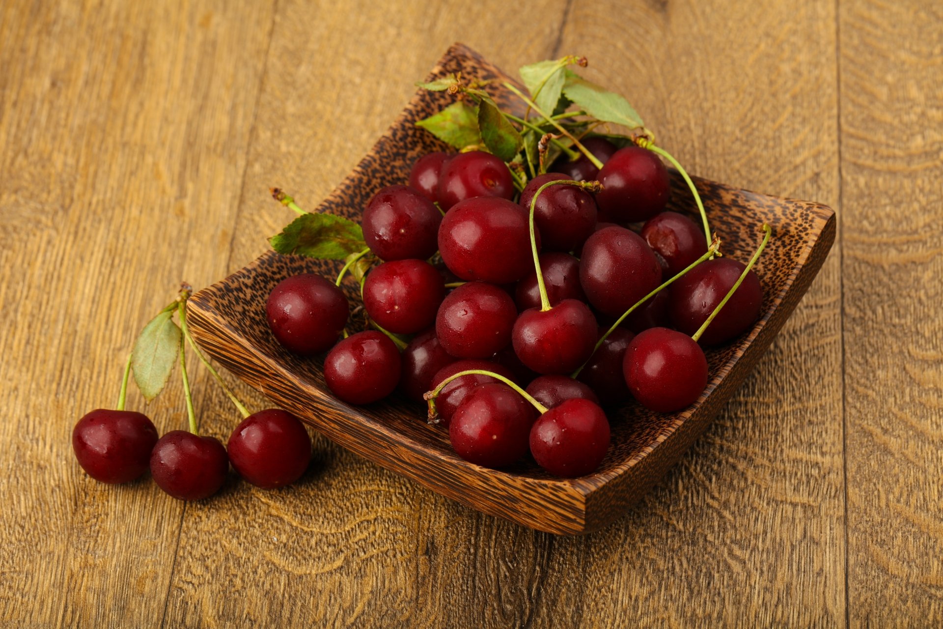8K Ultra HD PC desktop wallpaper showing ripe cherries (fruit, food) heaped in a wooden bowl on a rustic wood table.