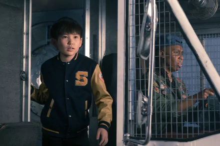 5K Ultra HD desktop wallpaper: a Ready Player One movie still showing two young actors in a metal booth — one in a varsity jacket, the other at the wheel, tense and alert.