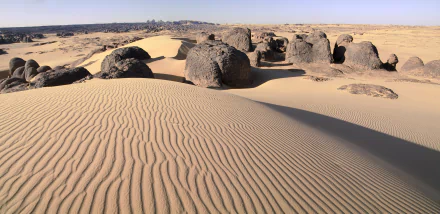 HD desktop wallpaper featuring the rippled sand dunes and rocky formations of Tassili N'Ajjer desert in Algeria, showcasing Africa's natural desert landscape.