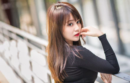 HD desktop wallpaper: portrait of a brunette model with long hair and lipstick, looking over her shoulder against a soft bokeh background with shallow depth of field.