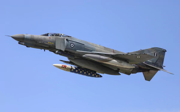 McDonnell Douglas F-4 Phantom II military jet fighter soars against a clear blue sky, showcased as a high-definition desktop wallpaper.