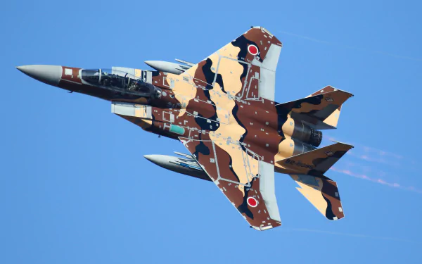 Mitsubishi F-15J jet fighter in tan-and-brown camouflage banking across a clear blue sky — military warplane HD PC desktop wallpaper background