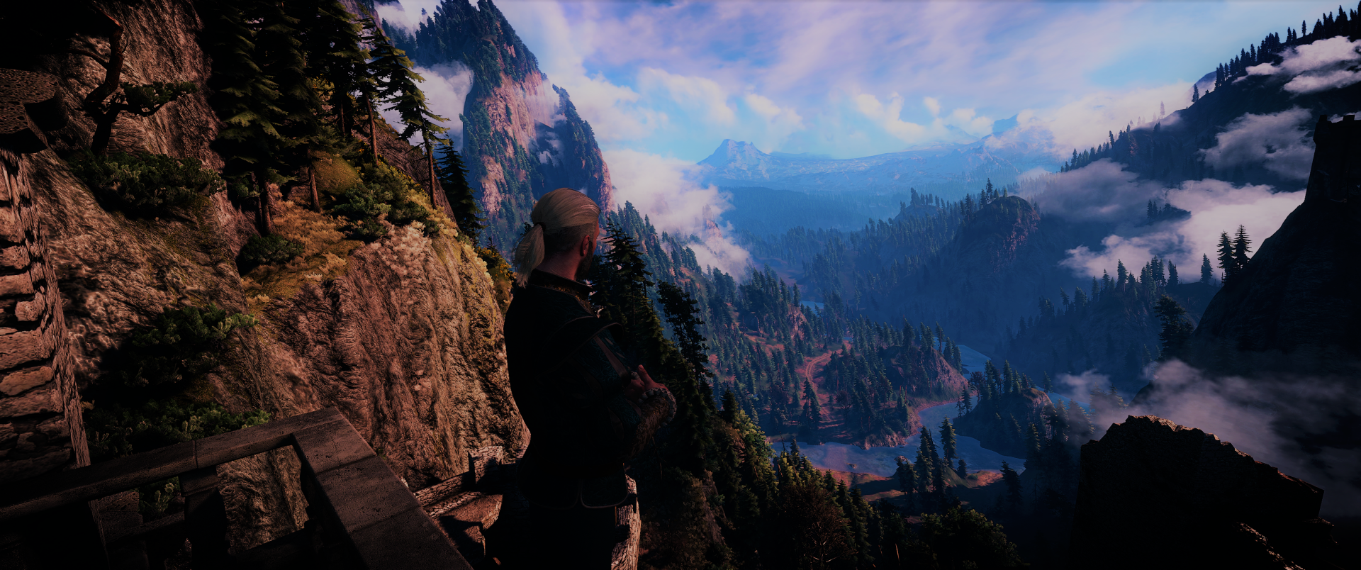 Geralt of Rivia from The Witcher 3: Wild Hunt stands on a cliff overlooking a vast, mountainous fantasy landscape in this HD PC desktop wallpaper.