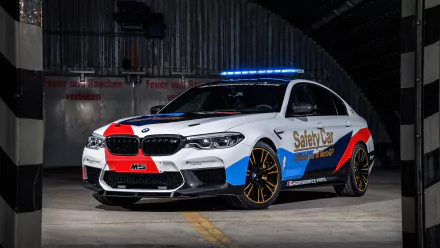 BMW M5 MotoGP Safety Car with blue lights on, showcased in a 4K Ultra HD desktop wallpaper, highlighting its sleek design and safety vehicle role.