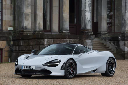 A high-definition desktop wallpaper featuring a sleek, white McLaren 720S coupé supercar parked in front of a stately, historic building.