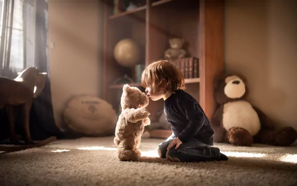 A little boy sits on the floor in a sunbeam, holding and facing a stuffed teddy bear in a softly lit room, captured in HD photography for a PC desktop wallpaper.