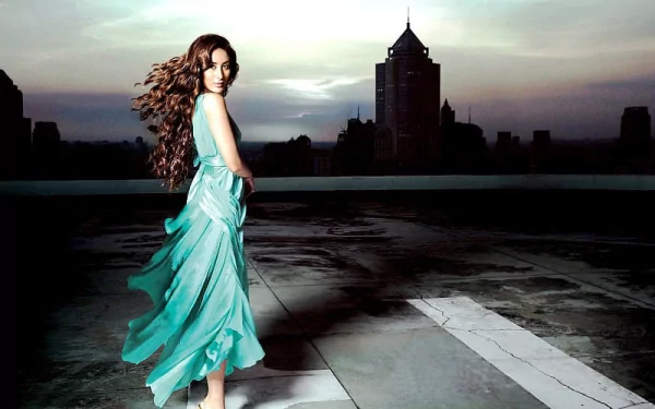 HD desktop wallpaper featuring celebrity Kareena Kapoor in a flowing turquoise dress, with a city skyline in the background at dusk.