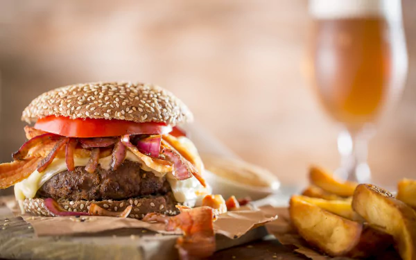 4K Ultra HD PC desktop wallpaper featuring a juicy bacon cheeseburger with tomato, lettuce, and fries, accompanied by a blurred glass of beer in the background.