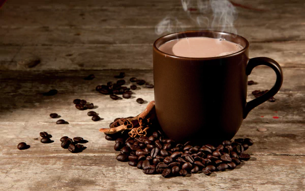 A steaming cup of coffee with cinnamon sticks and coffee beans scattered around on a rustic wooden table, featured in a high-definition still life wallpaper background.