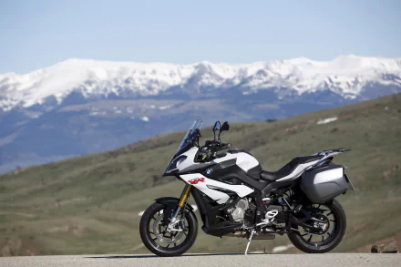 BMW S1000 XR (BMW S1000) motorcycle vehicle parked on a country road with snow-capped mountains in the background — 4K Ultra HD PC desktop wallpaper.