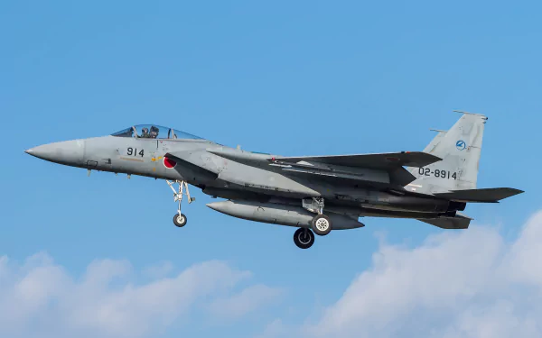A Mitsubishi F-15J jet fighter warplane in flight against a clear blue sky, showcasing its military design.