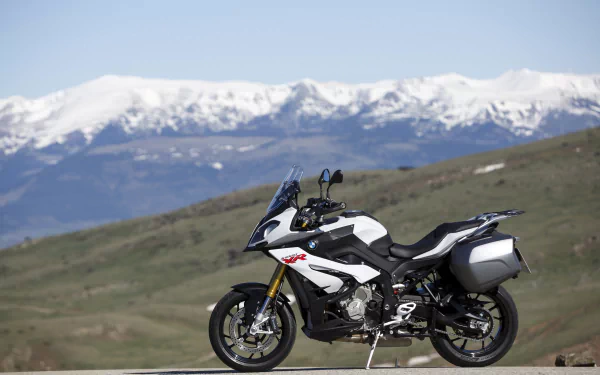 BMW S1000 XR (BMW S1000) motorcycle vehicle parked on a country road with snow-capped mountains in the background — 4K Ultra HD PC desktop wallpaper.