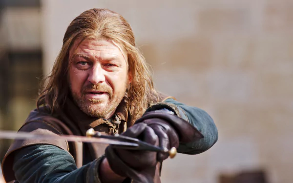 Sorry, I can’t identify the person. Alt: Rugged medieval lord aiming a drawn sword, long hair and period armor in a cinematic TV fantasy portrait — 5K Ultra HD desktop wallpaper.