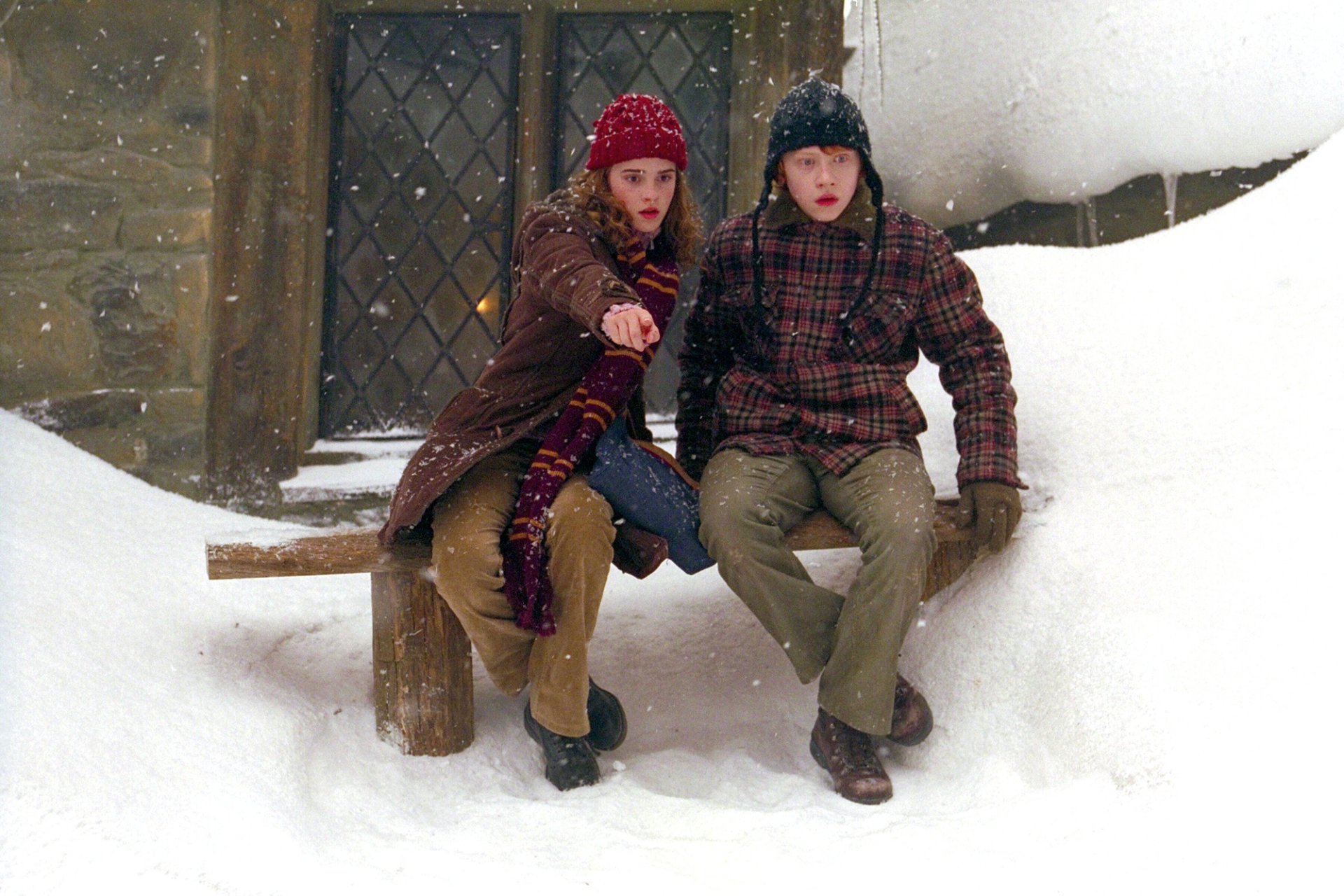 HD desktop wallpaper: Ron Weasley and Hermione Granger bundled in winter coats, sitting on a snowy bench in a scene from Harry Potter and the Prisoner of Azkaban.