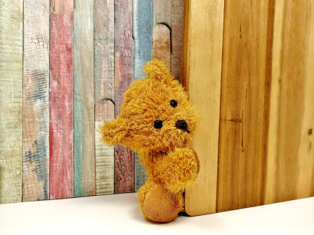 HD wallpaper featuring a cute teddy bear stuffed animal with a textured wooden background in soft pastel colors.