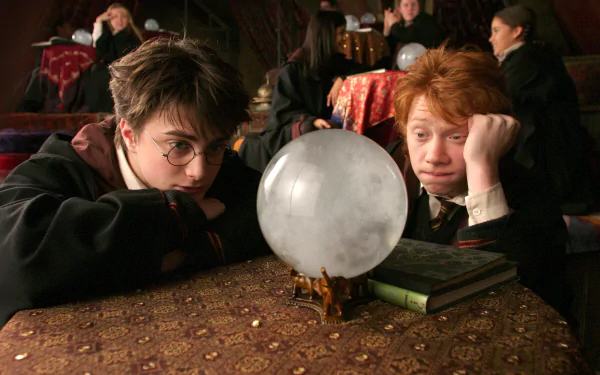 Harry Potter and Ron Weasley intently watch a glowing crystal ball at a table in this HD movie scene from Harry Potter and the Prisoner of Azkaban.