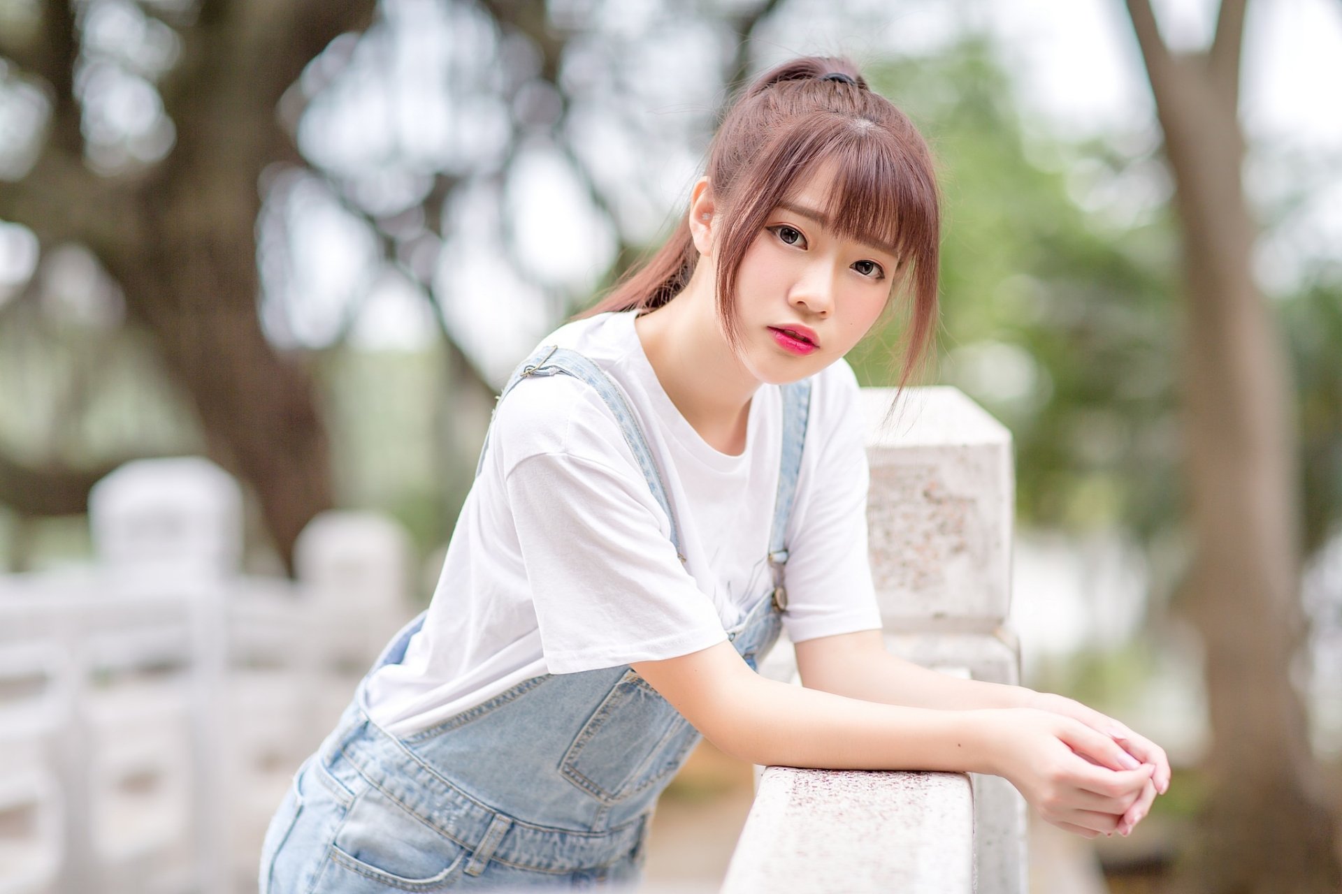 Brunette Asian woman with lipstick poses outdoors, captured with depth of field for a crisp HD PC desktop wallpaper and background.