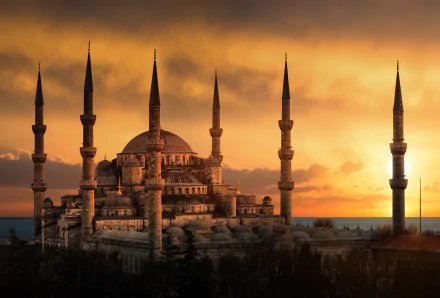8K Ultra HD wallpaper of the Sultan Ahmed Mosque at sunset, showcasing its majestic domes and minarets against a vibrant, glowing sky.