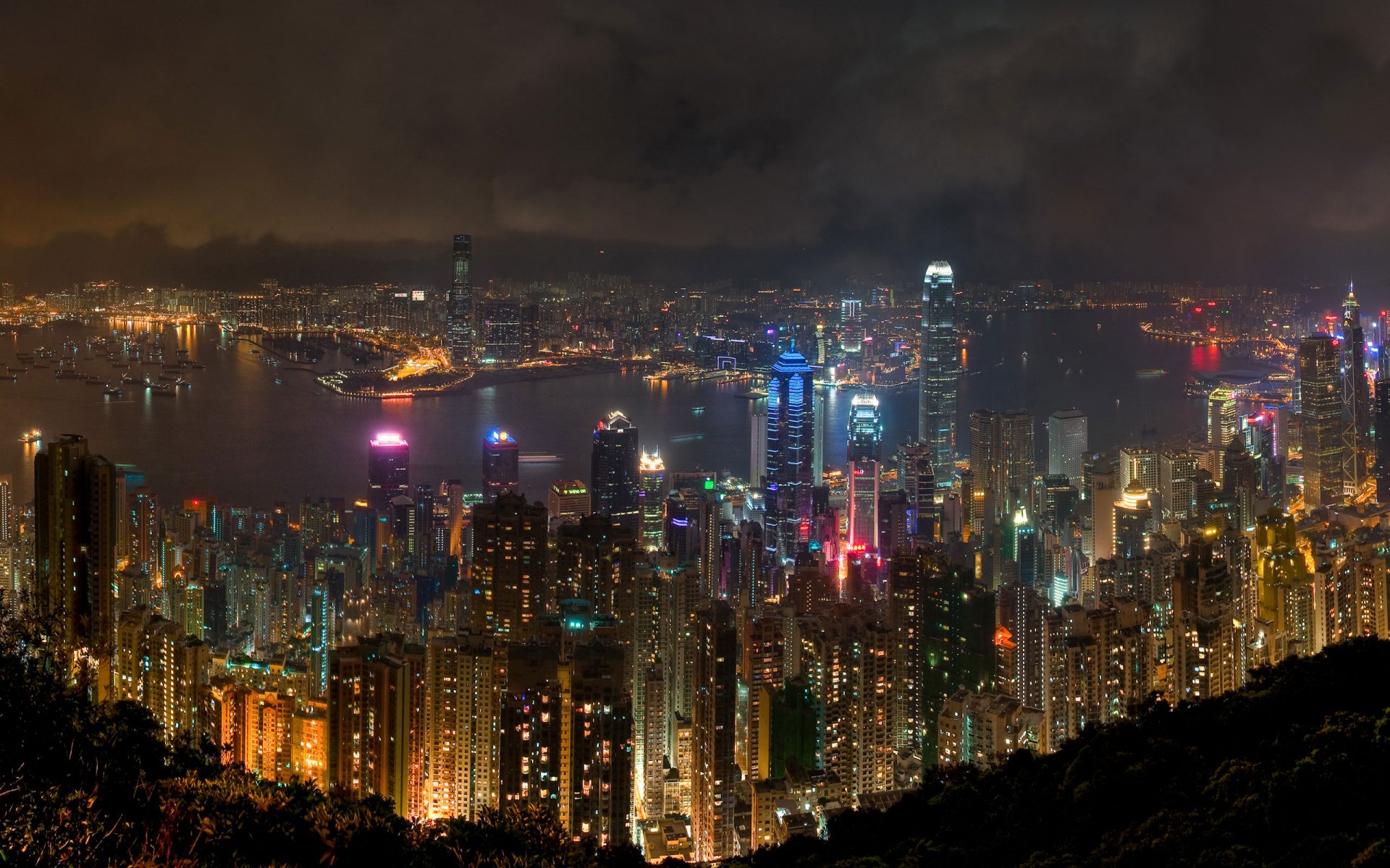 HD desktop wallpaper showcasing a vibrant nighttime view of Hong Kong’s illuminated skyline and harbor, highlighting its dense urban landscape and man-made structures.