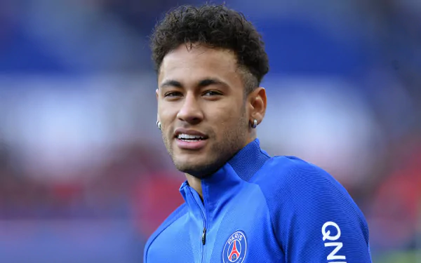HD PC desktop wallpaper of a Brazilian soccer star in a blue training jacket, smiling on the pitch — sports-themed background.