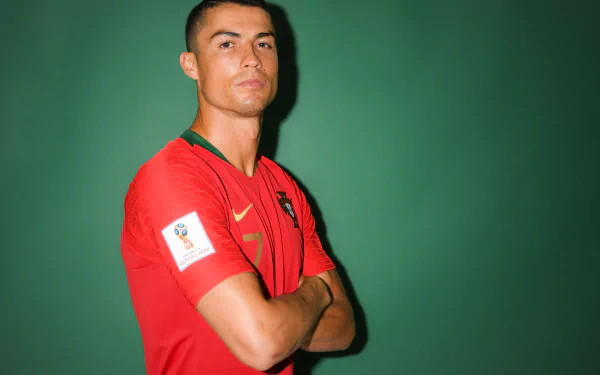 HD desktop wallpaper of Portuguese soccer player Cristiano Ronaldo confidently posing in a red jersey against a green background.