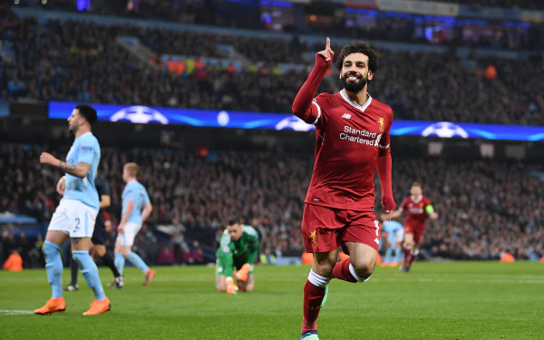HD PC desktop wallpaper featuring Egyptian soccer star Mohamed Salah in his Liverpool kit celebrating a goal during a match, capturing the excitement of sports.
