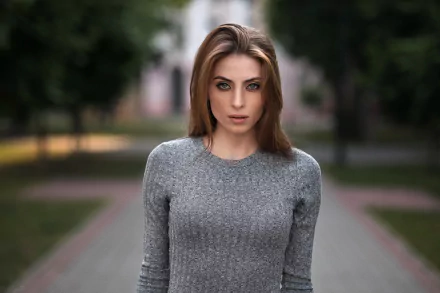 HD desktop wallpaper of a brunette woman with blue eyes, captured with a shallow depth of field that softly blurs the background, highlighting her intense gaze.