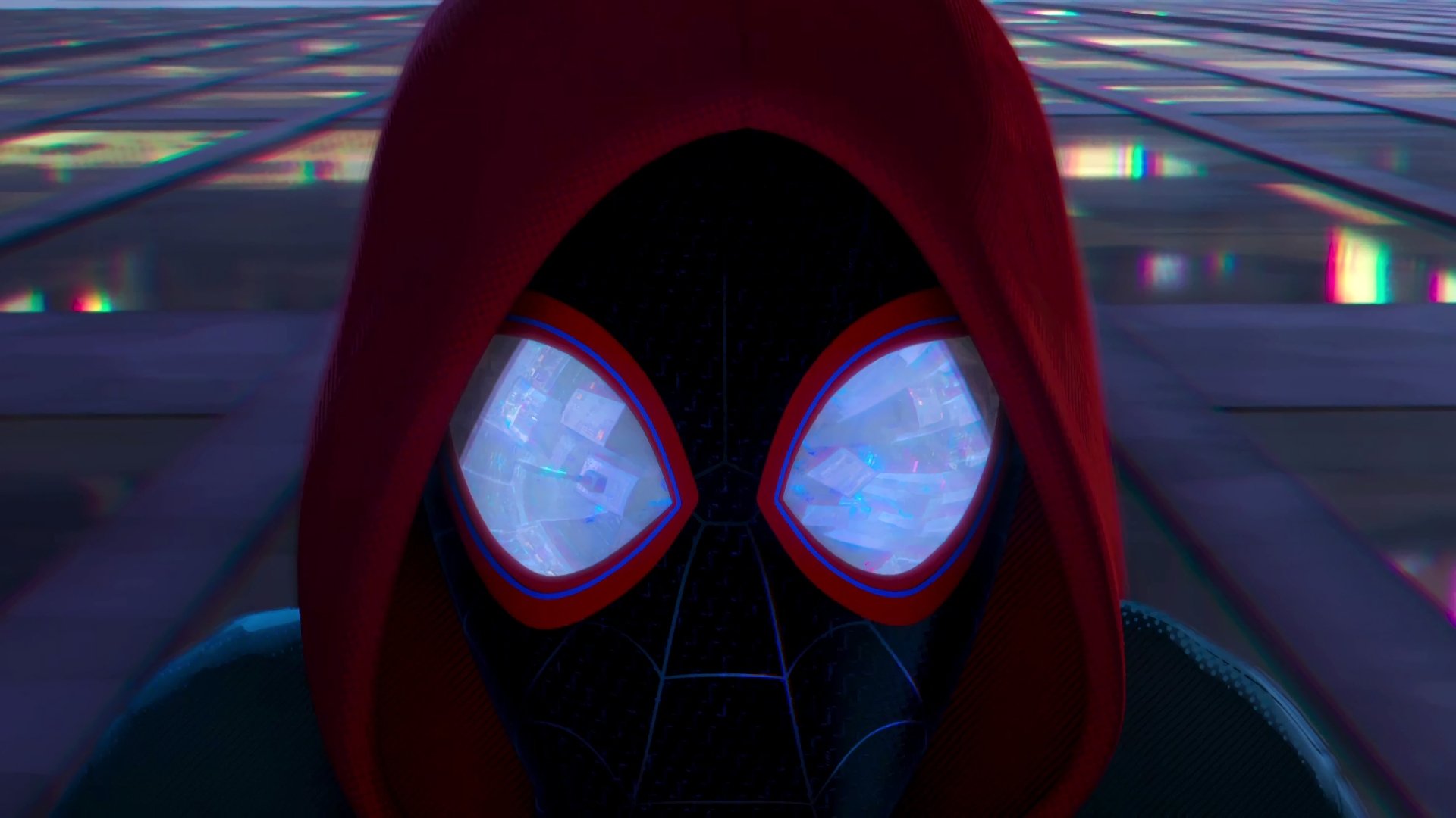 Close-up of Miles Morales as Spider-Man from the movie Spider-Man: Into The Spider-Verse, wearing a red hood, set against a cityscape background. HD desktop wallpaper and background.