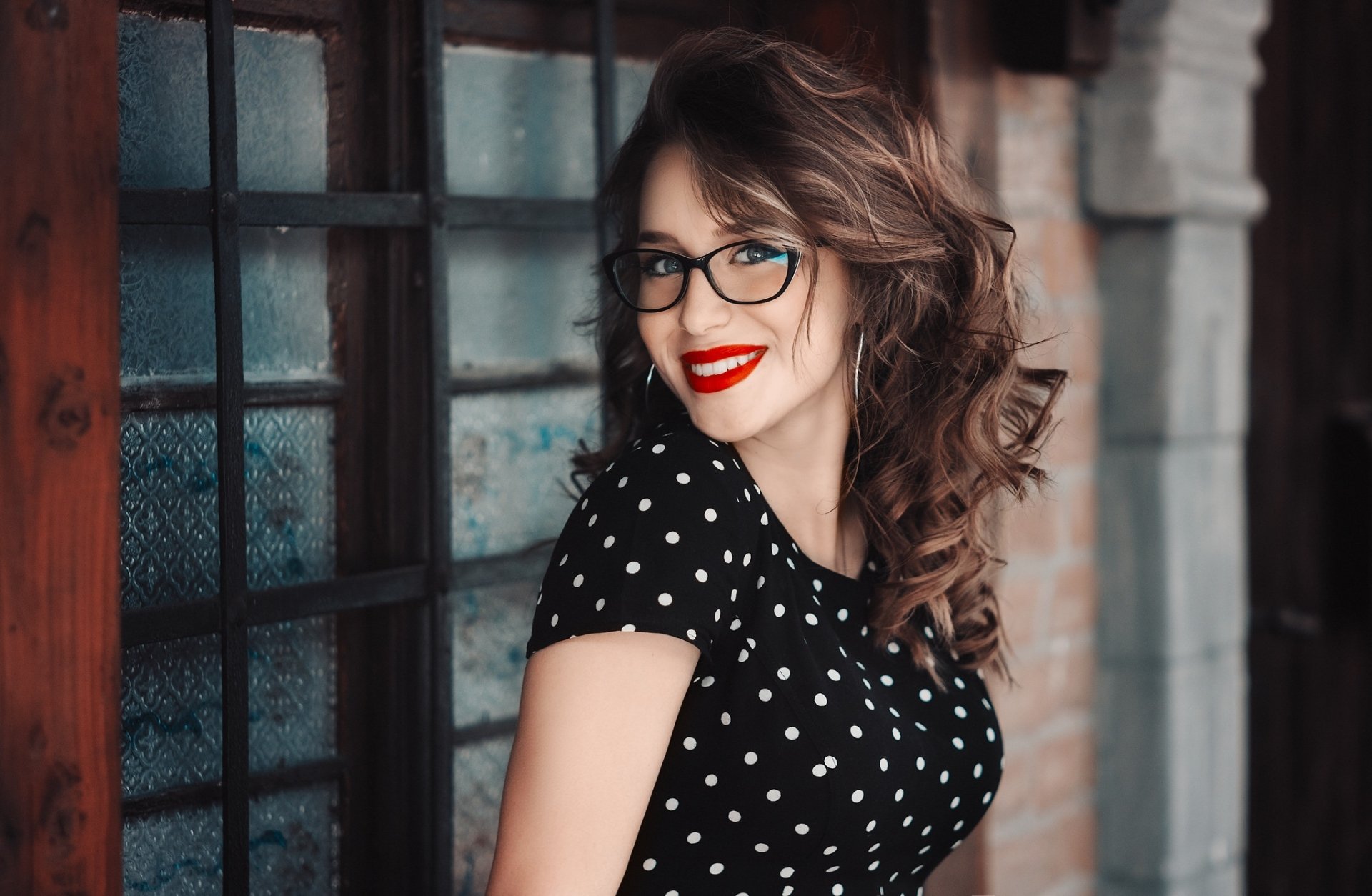 Brunette woman model with glasses and bright lipstick smiles confidently against a textured background in this HD PC desktop wallpaper.