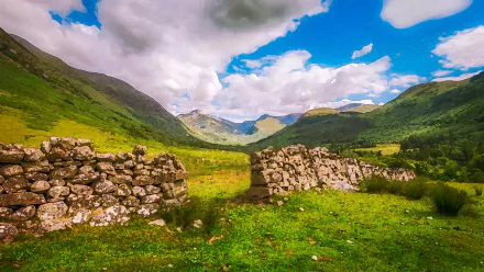 4K Ultra HD landscape featuring a man-made stone wall set in lush green hills under a cloud-filled sky.