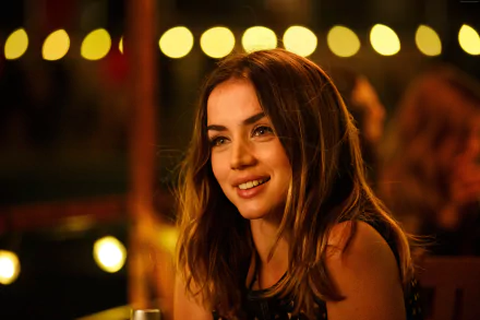 HD wallpaper featuring Ana de Armas smiling brightly in a scene from the movie Overdrive, with a warm, softly lit background of blurred circular lights.