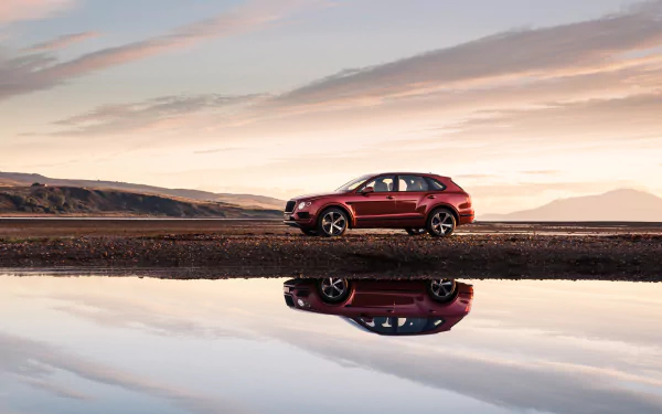 Red Bentley Bentayga SUV car parked by a lakeshore at sunset, reflected in still water — 4K Ultra HD PC desktop wallpaper and background.
