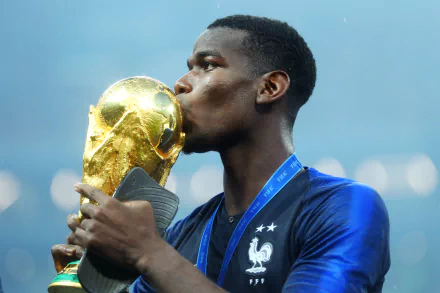 HD desktop wallpaper featuring a soccer player kissing the World Cup trophy against a blurred stadium backdrop.