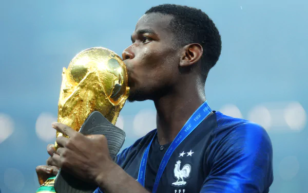 HD desktop wallpaper featuring a soccer player kissing the World Cup trophy against a blurred stadium backdrop.