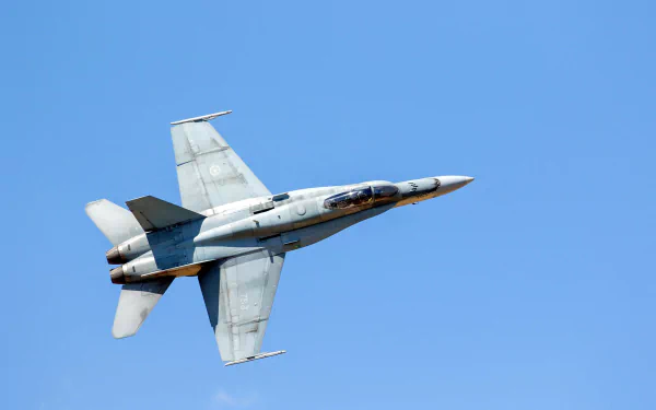 High-definition desktop wallpaper of a McDonnell Douglas CF-18 Hornet jet fighter soaring against a clear blue sky, showcasing its sleek military aircraft design.