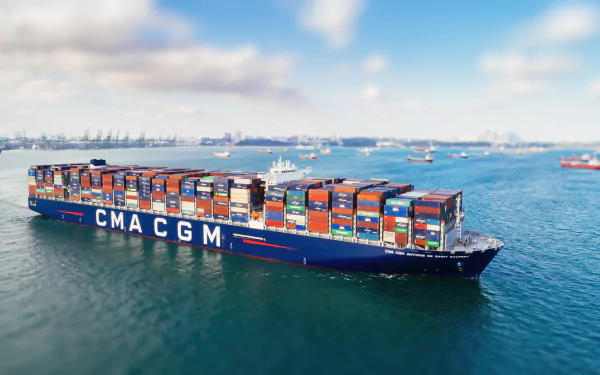 HD desktop wallpaper featuring the CMA CGM Antoine De Saint Exupery container ship carrying numerous colorful vehicles across calm waters.