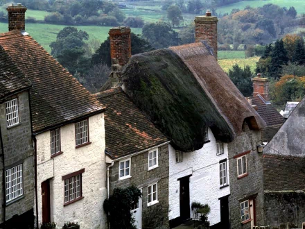 A picturesque view of charming man-made buildings with thatched roofs, set against a lush green landscape, creating an inviting HD desktop wallpaper and background.