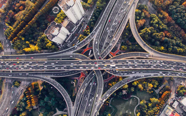 Aerial 4K Ultra HD view of a complex man-made highway interchange surrounded by greenery in Shanghai, China, showcasing urban infrastructure and traffic flow.