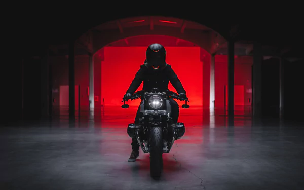 HD PC desktop wallpaper featuring a sleek BMW R nineT motorcycle with a rider in dark gear, set against a dramatic red-lit background in an industrial space.