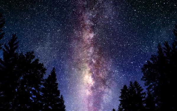 A stunning HD wallpaper featuring the Milky Way galaxy, set against a backdrop of silhouetted trees, capturing the essence of sci-fi wonder and cosmic beauty.