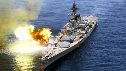 HD desktop wallpaper of the military warship USS Iowa (BB-61) in action, with its main guns firing over the ocean.
