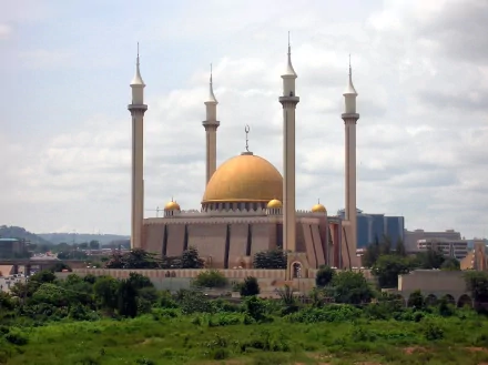 A stunning view of the Abuja National Mosque, featuring its golden dome and tall minarets, set against a cloudy sky. This HD image captures the grandeur of this iconic religious building.