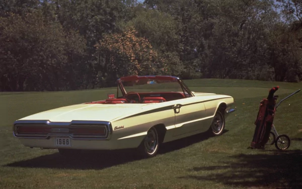 HD desktop wallpaper featuring a vintage Ford Thunderbird convertible parked on a grassy lawn with golf clubs nearby and trees in the background.