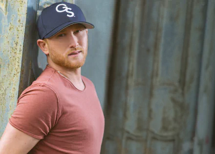 HD desktop wallpaper featuring Cole Swindell in a casual pose with a cap, set against a rustic backdrop.