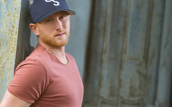HD desktop wallpaper featuring Cole Swindell in a casual pose with a cap, set against a rustic backdrop.